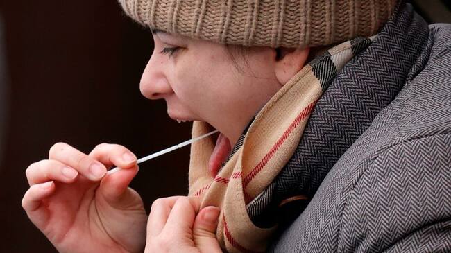 A woman swabs her throat at a coronavirus testing site set up at the Bramley Inn in the village of Bramley, west of London, on February 17, 2021 as part of surge testing to monitor and suppress the spread of the Covid-19 variant first identified in South Africa. (Photo by Adrian DENNIS / AFP) (Photo by ADRIAN DENNIS/AFP via Getty Images)