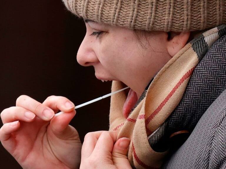 A woman swabs her throat at a coronavirus testing site set up at the Bramley Inn in the village of Bramley, west of London, on February 17, 2021 as part of surge testing to monitor and suppress the spread of the Covid-19 variant first identified in South Africa. (Photo by Adrian DENNIS / AFP) (Photo by ADRIAN DENNIS/AFP via Getty Images)