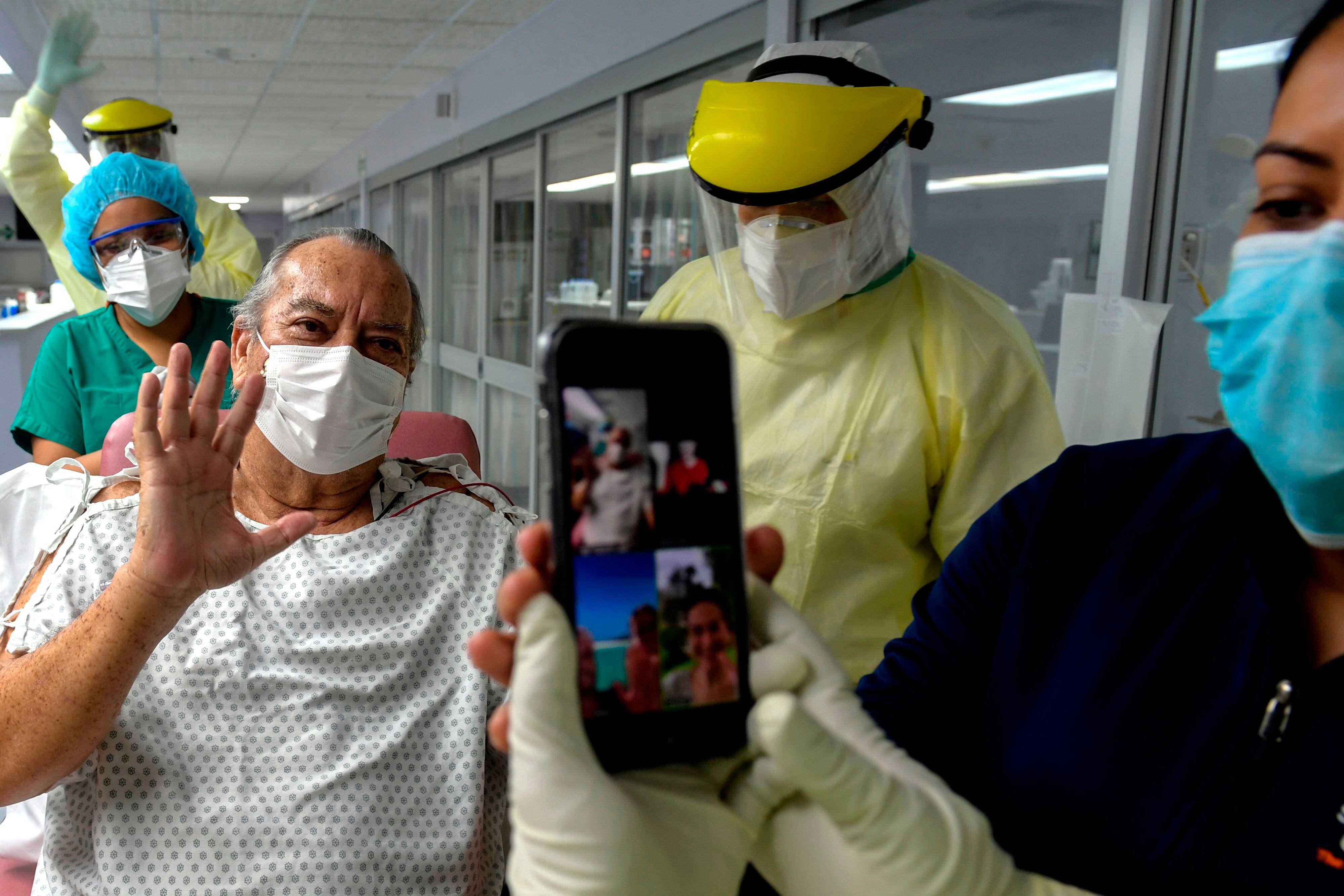 Panama's Herman Bern (L), a confirmed case of COVID-19, waves his family through a video-conference at the intensive care unit of Paitilla Hospital, after his last COVID-19 test turned out negative, in Panama City, on May 6, 2020. - Bern spent 50 days in the intensive care unit due to COVID-19.Panama accumulated 218 deceased people and nearly 8,000 infections by COVID-19. About a thousand of those infected are in isolation at home or in hotels, 270 are hospitalized on the ground and 88 in the intensive care unit. (Photo by Luis ACOSTA / AFP) (Photo by LUIS ACOSTA/AFP via Getty Images)