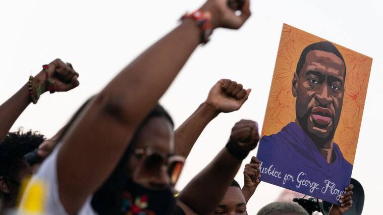TOPSHOT - People raise their fists and hold a portrait of George Floyd during a rally following the guilty verdict the trial of Derek Chauvin on April 20, 2021, in Atlanta, Georgia. - Derek Chauvin, a white former Minneapolis police officer, was convicted on April 20 of murdering African-American George Floyd after a racially charged trial that was seen as a pivotal test of police accountability in the United States. (Photo by Elijah Nouvelage / AFP) (Photo by ELIJAH NOUVELAGE/AFP via Getty Images)