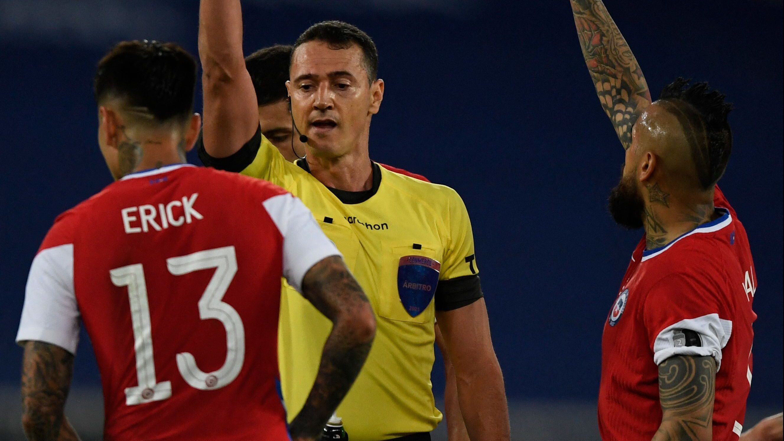 Colombian referee Wilmar Roldan shows the yellow card to Chile's Erick Pulgar (L) as he conducts the Conmebol Copa America 2021 football tournament group phase match between Argentina and Chile at the Nilton Santos Stadium in Rio de Janeiro, Brazil, on June 14, 2021. (Photo by MAURO PIMENTEL / AFP) (Photo by MAURO PIMENTEL/AFP via Getty Images)