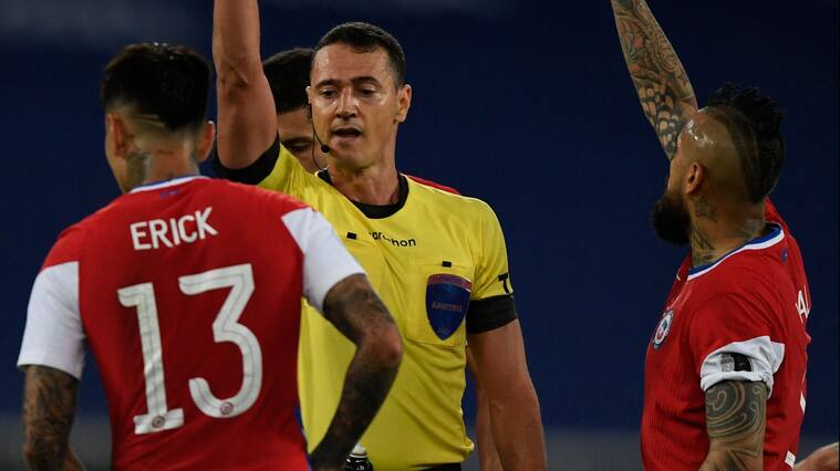 Colombian referee Wilmar Roldan shows the yellow card to Chile's Erick Pulgar (L) as he conducts the Conmebol Copa America 2021 football tournament group phase match between Argentina and Chile at the Nilton Santos Stadium in Rio de Janeiro, Brazil, on June 14, 2021. (Photo by MAURO PIMENTEL / AFP) (Photo by MAURO PIMENTEL/AFP via Getty Images)