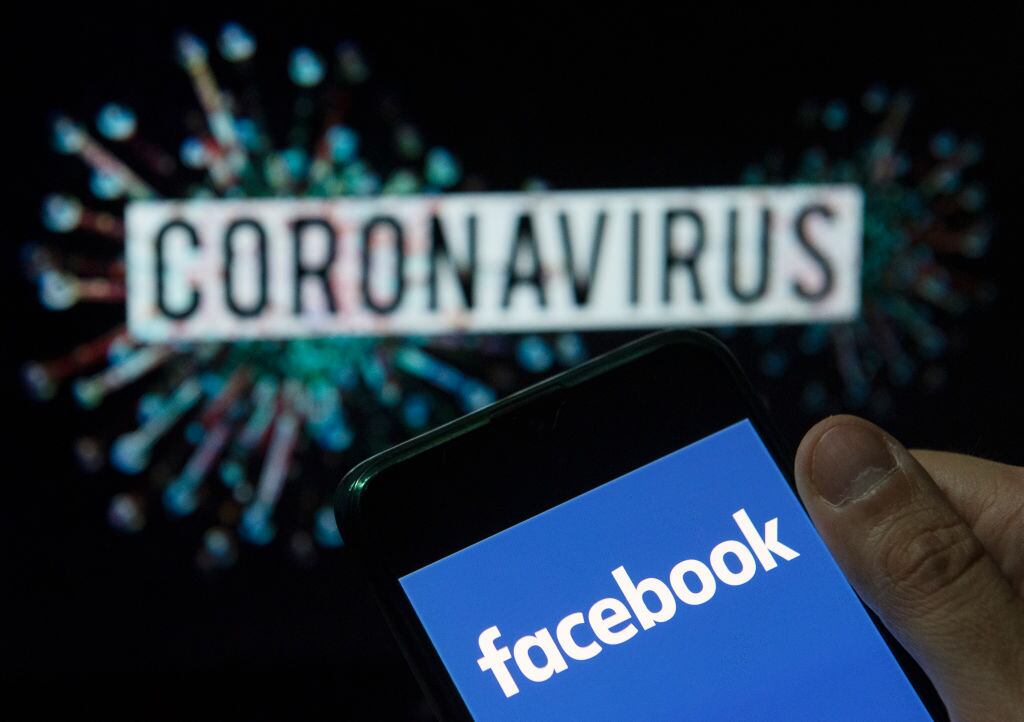 CHINA - 2020/03/24: In this photo illustration the American online social media and social networking service company Facebook logo seen displayed on a smartphone with a computer model of the COVID-19 coronavirus on the background. (Photo Illustration by Budrul Chukrut/SOPA Images/LightRocket via Getty Images)