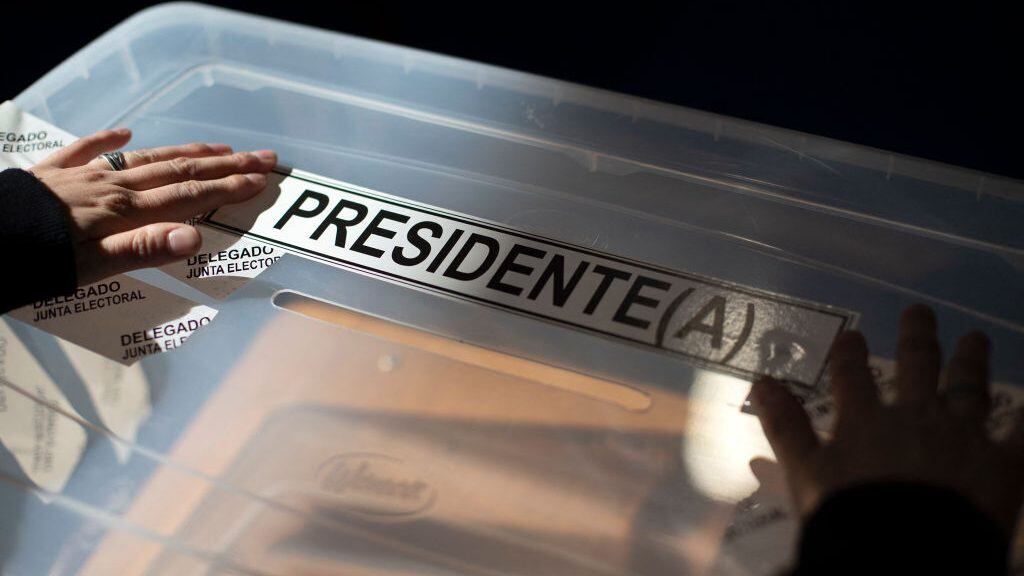 A woman places a sticker reading "President" on a ballot box during the set up of polling stations at the Portugal highschool in Punta Arenas, Chile, on November 20, 2021, on the eve of Chile's general elections. - Seven candidates will contest Chile's presidential elections, with polls showing two clear favorites in opposing political camps: Gabriel Boric, 35, of the leftist Approve Dignity alliance which includes the Communist Party, and far right candidate Jose Antonio Kast, 55, of the Republican Party -- each with about a quarter of stated voter intention. (Photo by CLAUDIO REYES / AFP) (Photo by CLAUDIO REYES/AFP via Getty Images)
