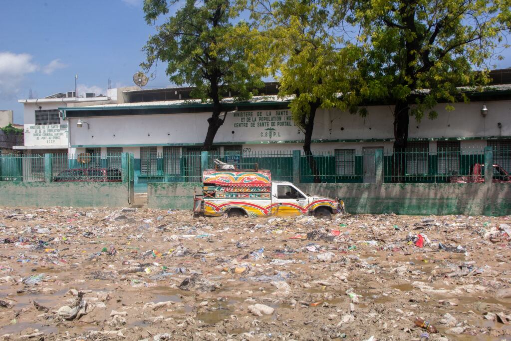 Un auto intenta avanzar por las calles inundadas y el barro en Puerto Príncipe