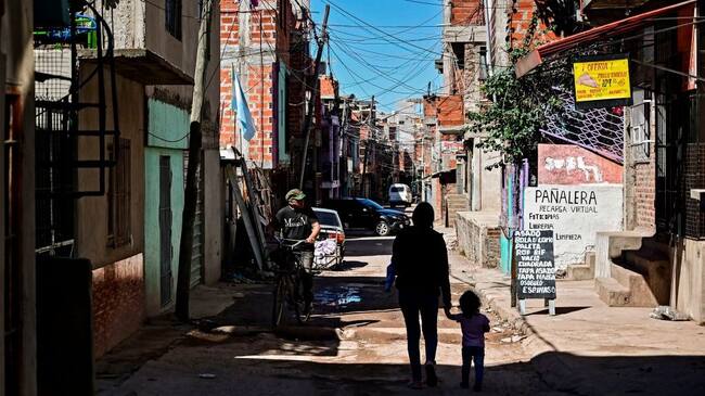A woman and a child walk as a man rides a bycicle along a street at the Villa 21-24 shantytown in Buenos Aires on September 29, 2020, amid the new coronavirus pandemic. - Argentina's economy contracted 12.6% in the first seven months of 2020 compared to the same period last year, in the midst of the covid-19 pandemic, the state-run statistics institute INDEC reported Monday. (Photo by RONALDO SCHEMIDT / AFP) (Photo by RONALDO SCHEMIDT/AFP via Getty Images)