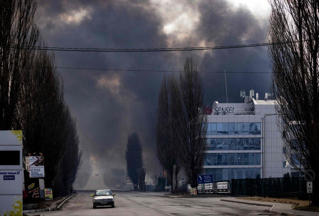 Un auto pasa en medio de los incendios que dejan los ataques cerca de Kiev