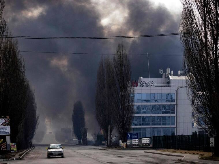 Un auto pasa en medio de los incendios que dejan los ataques cerca de Kiev
