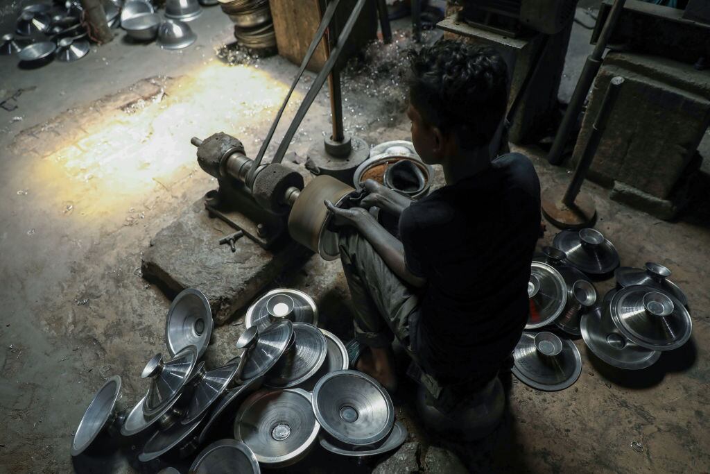 Un niño limpia piezas metálicas en Bangladesh