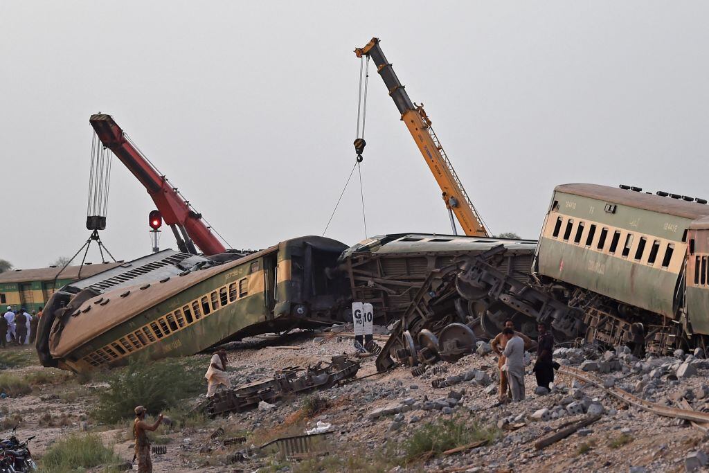 La maquinaria levanta los carros de un tren accidentado en Sindh de Pakistán
