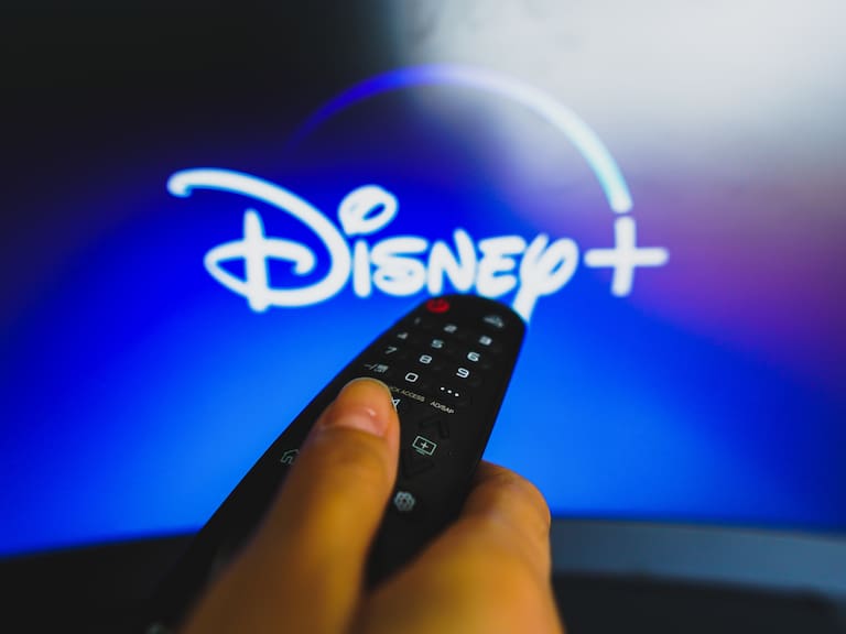 BRAZIL - 2022/05/10: In this photo illustration, a hand holding a TV remote control in front of the Disney Plus logo on a TV screen. (Photo Illustration by Rafael Henrique/SOPA Images/LightRocket via Getty Images)