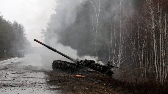 TOPSHOT - Smoke rises from a Russian tank destroyed by the Ukrainian forces on the side of a road in Lugansk region on February 26, 2022. - Russia on February 26 ordered its troops to advance in Ukraine "from all directions" as the Ukrainian capital Kyiv imposed a blanket curfew and officials reported 198 civilian deaths. (Photo by Anatolii Stepanov / AFP) (Photo by ANATOLII STEPANOV/AFP via Getty Images)