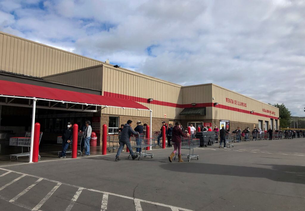 Los ciudadanos mexicanos hacen una fila para ingresar a un supermercado en Tijuana