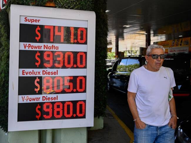 Un hombre camina por una estación ante el cartel que muestra el fuerte aumento en el precio de los combustibles en Argentina durante el gobierno de Milei.