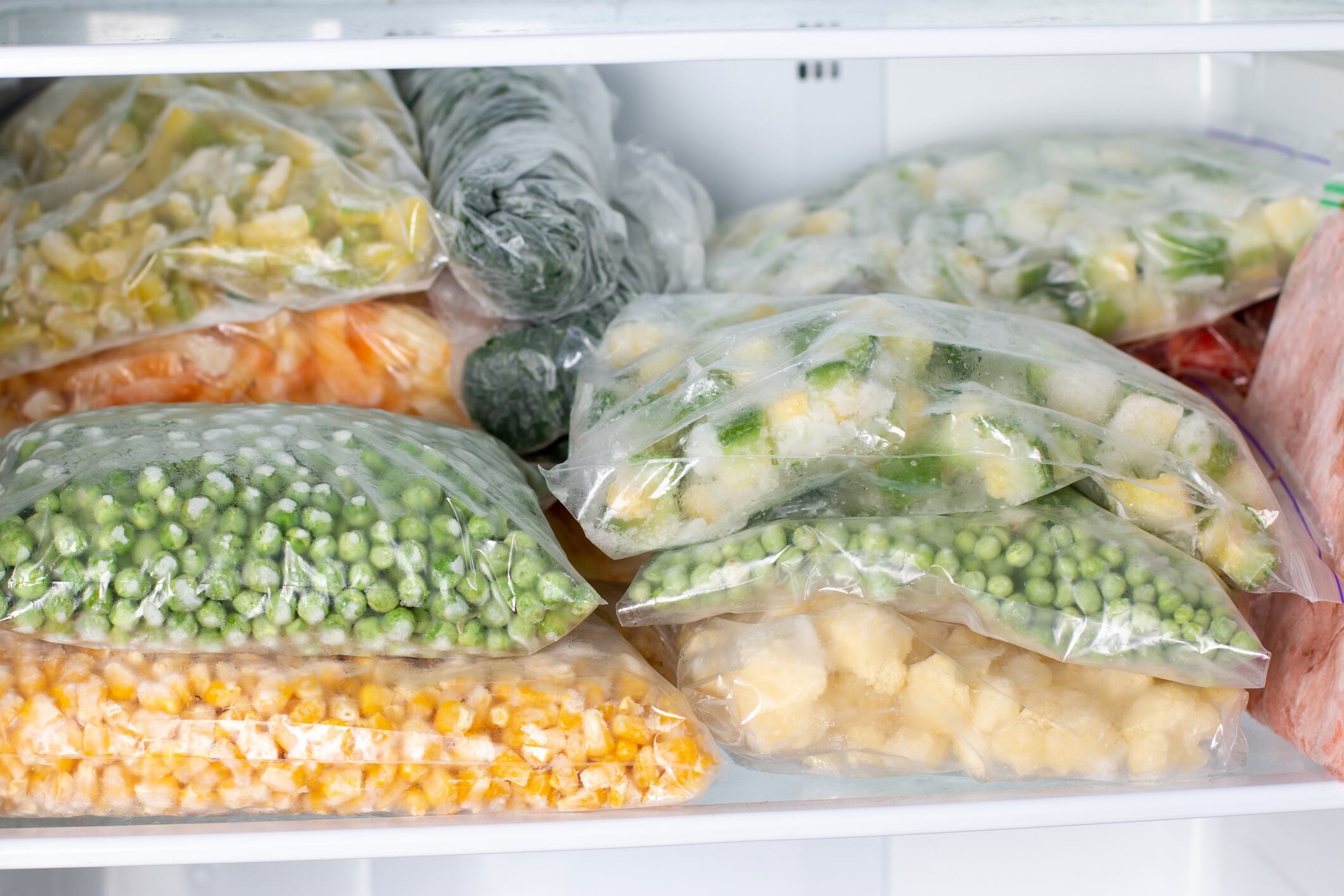 Plastic bags with deep frozen vegetables in refrigerator