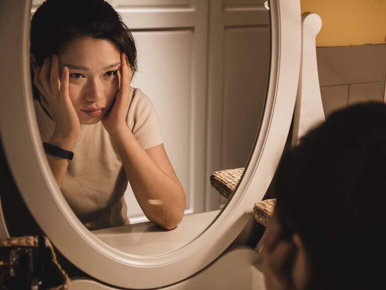 Asian woman sitting in front of the dressing table feeling depressed