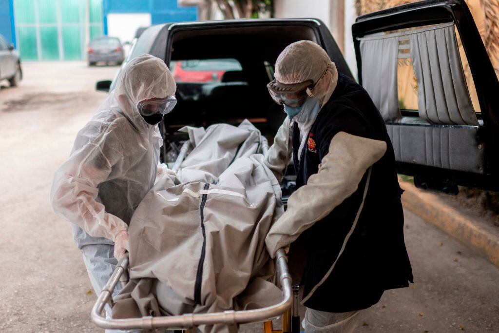 Trabajadores de una funeraria llevan a una víctima del coronavirus