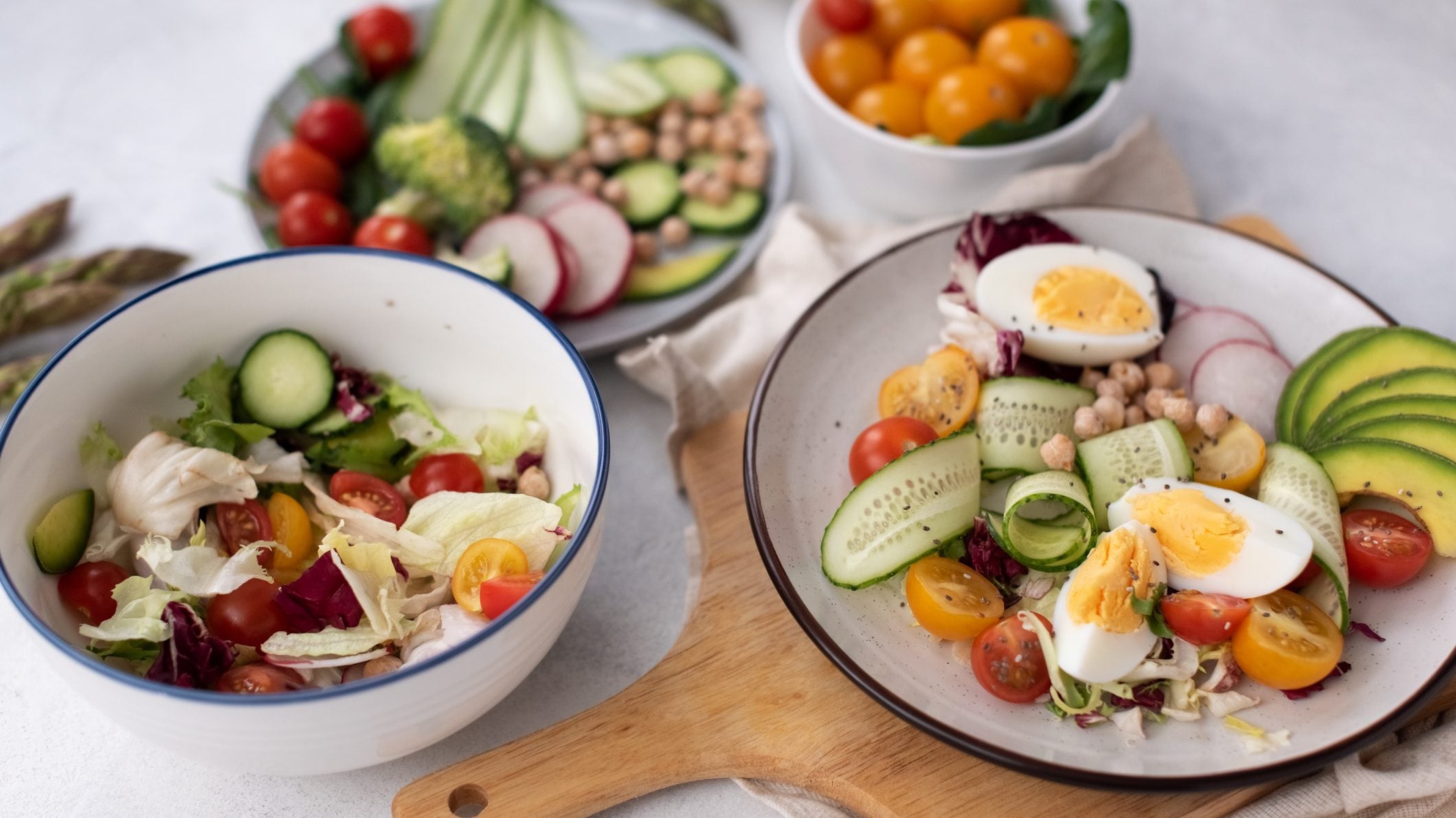 Healthy detox dish with egg, avocado, quinoa, spinach, fresh tomato, green peas and broccoli on white wooden background, top view