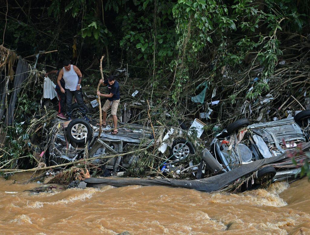 Personas buscan partes en vehículos atrapados por las inundaciones en Petrópolis