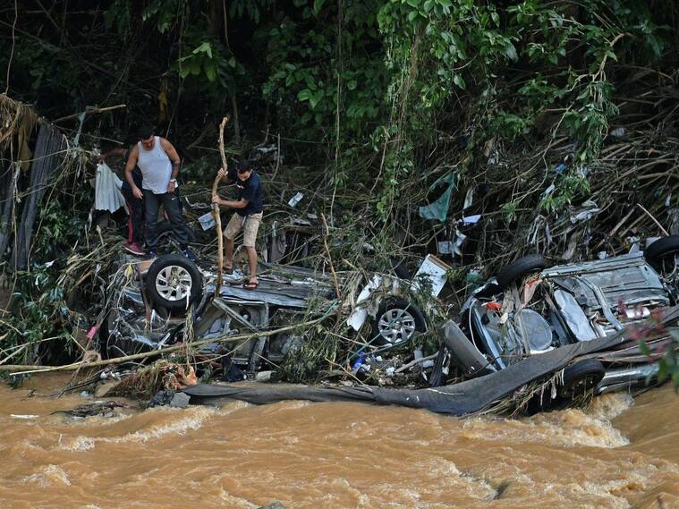 Personas buscan partes en vehículos atrapados por las inundaciones en Petrópolis