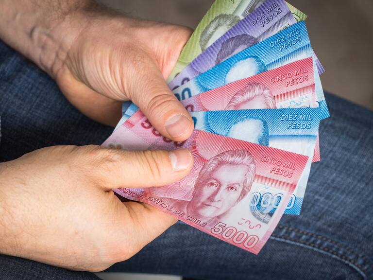 a man holding Chilean money in his hand, Pesos of various values
