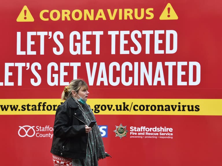 Mujer camina ante cartel que promueve la vacunación anticovid en Inglaterra
