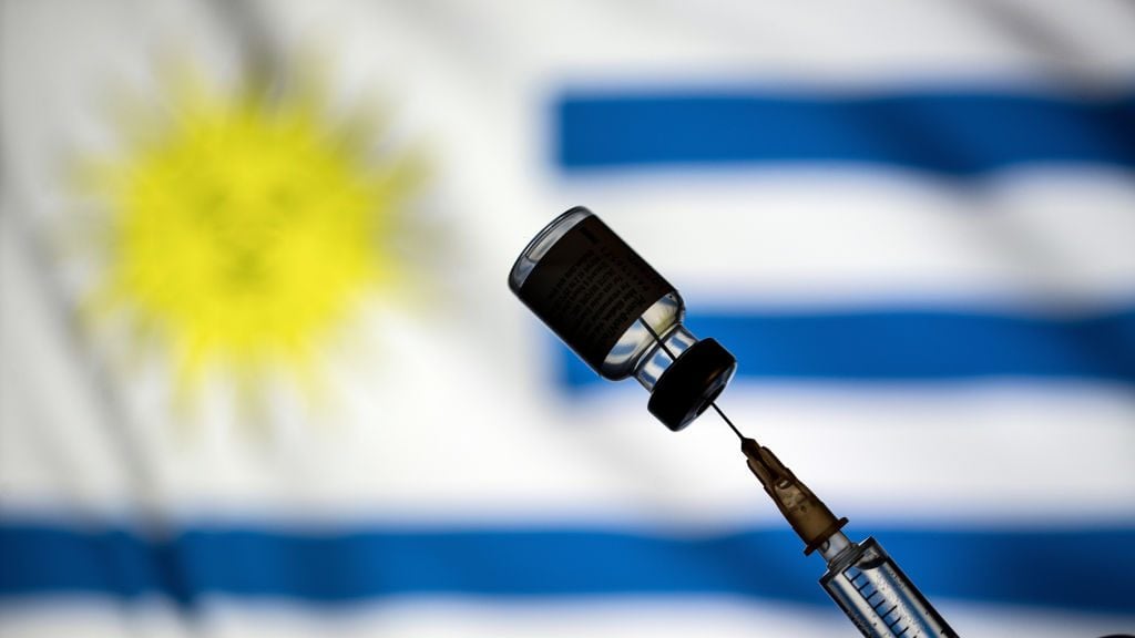 POLAND - 2021/01/24: In this photo illustration a vial of covid-19 vaccine and a medical syringe displayed over the Uruguay flag. (Photo Illustration by Vito Corleone/SOPA Images/LightRocket via Getty Images)