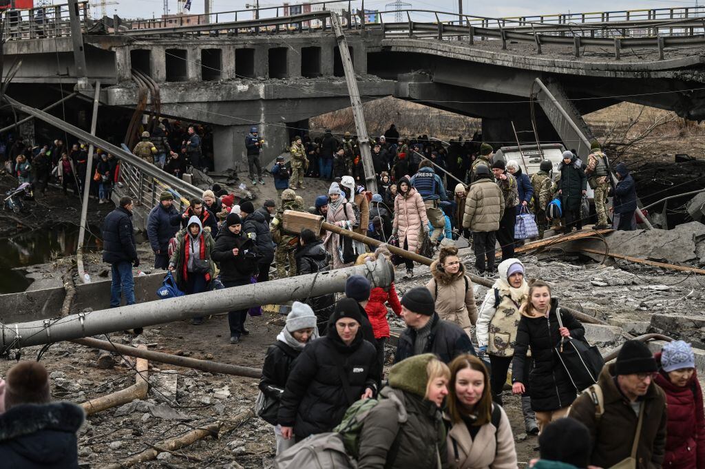 La gente cruza un puente destruido mientras evacuan la ciudad de Irpin, al noroeste de Kiev, durante fuertes bombardeos y bombardeos el 5 de marzo de 2022, 10 días después de que Rusia lanzara una invasión militar en Ucrania. (Foto de Aris Messinis / AFP) (Foto de ARIS MESSINIS/AFP vía Getty Images)