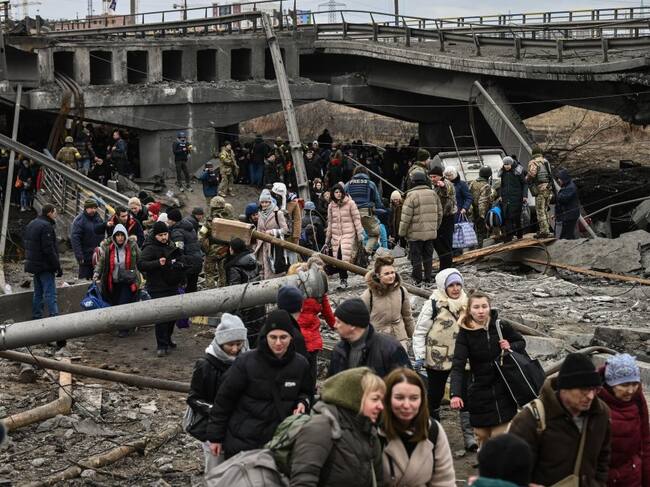 La gente cruza un puente destruido mientras evacuan la ciudad de Irpin, al noroeste de Kiev, durante fuertes bombardeos y bombardeos el 5 de marzo de 2022, 10 días después de que Rusia lanzara una invasión militar en Ucrania. (Foto de Aris Messinis / AFP) (Foto de ARIS MESSINIS/AFP vía Getty Images)
