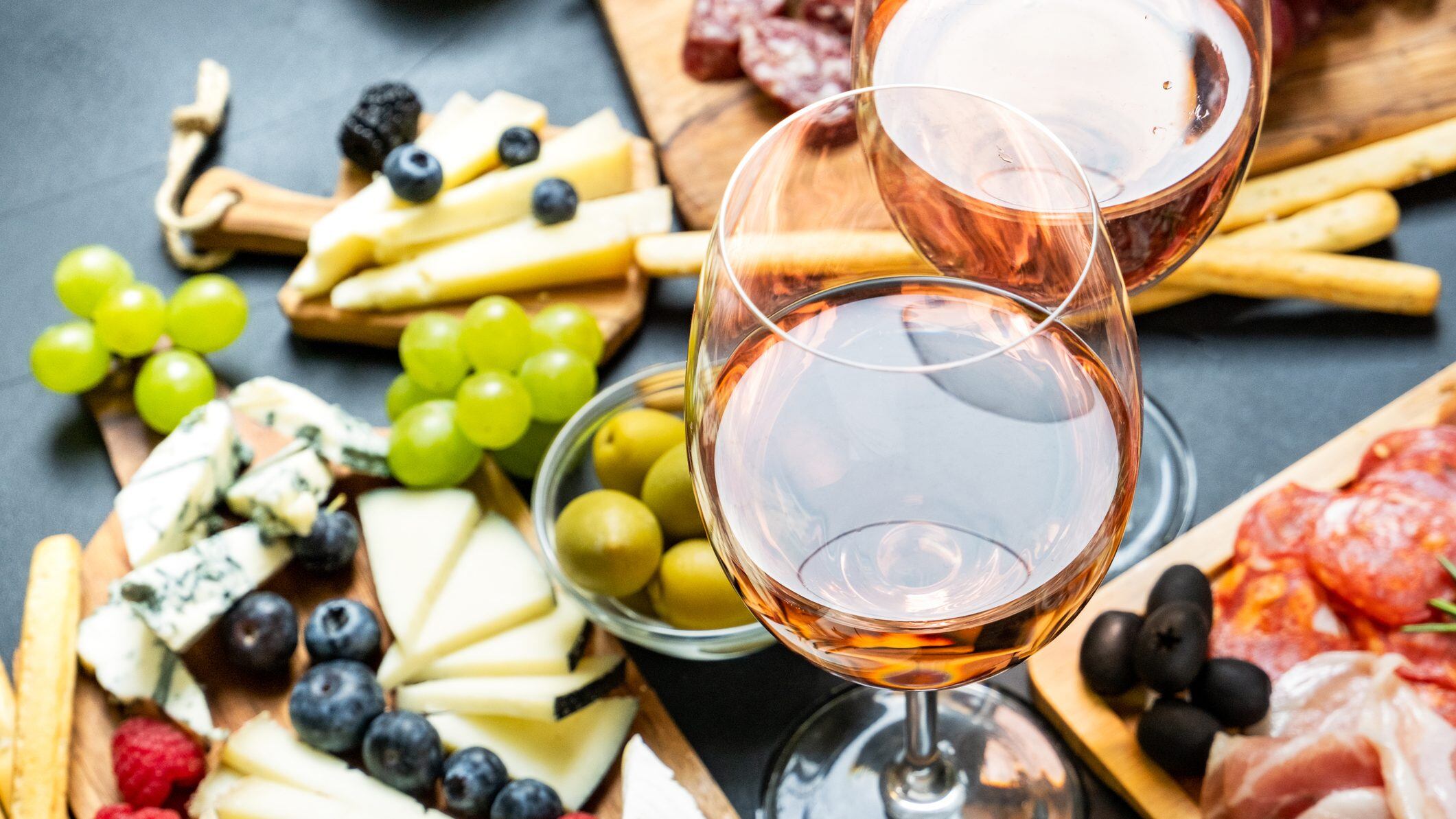 Aperitif two glasses of French rose wine with cheese and salami, olives and grapes
