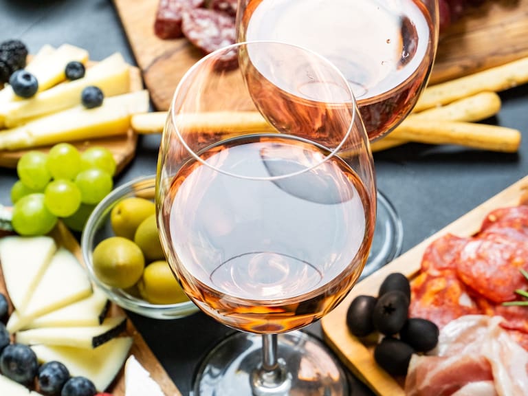 Aperitif two glasses of French rose wine with cheese and salami, olives and grapes