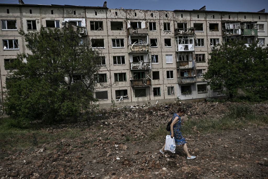 Mujer camina ante la destrucción que deja misil en Soledar del Donbás