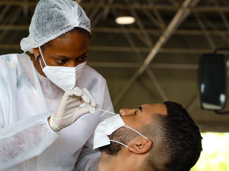 A health worker takes a swab sample from a resident to be tested for COVID-19, in Rio de Janeiro, Brazil, on January 19, 2022. (Photo by Ernesto Carrico/NurPhoto via Getty Images)