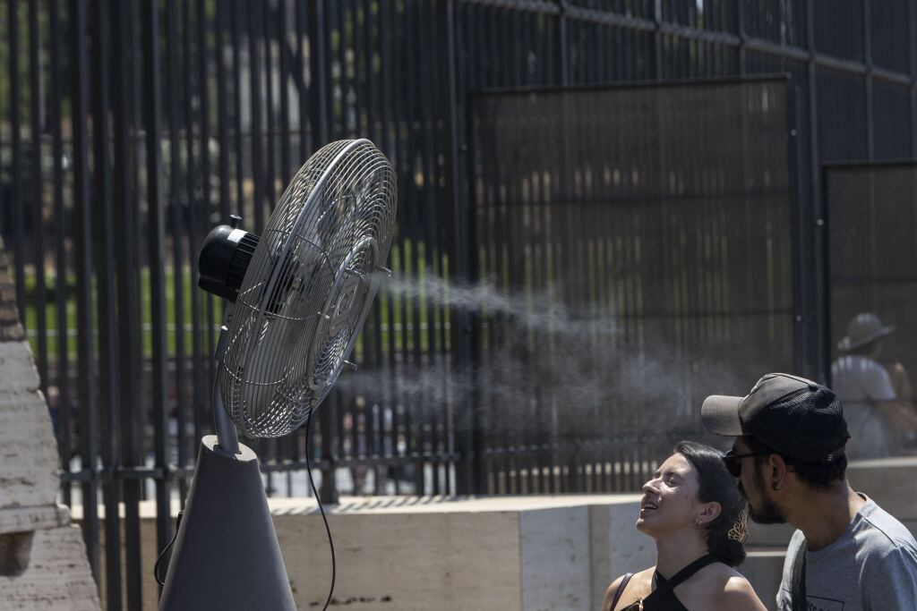 Personas se acercan a un ventilador en las calles de Roma ante el calor extremo