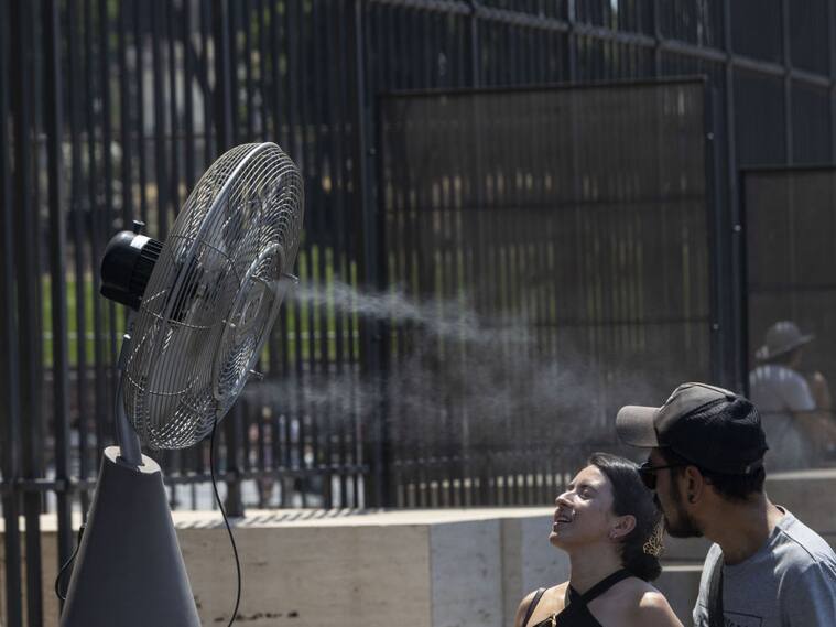 Personas se acercan a un ventilador en las calles de Roma ante el calor extremo