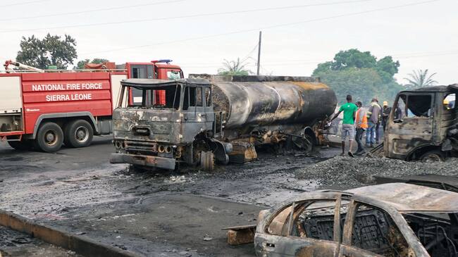A man walks past burnt vehicules in Freetown on November 6, 2021, following a massive explosion that has killed at least 92 people. - According to witnesses, the accident happened when a vehicle caught fire at a petrol station after a road accident in the night of November 5 to 6. The flames then spread, burning people in cars and on roads nearby. (Photo by Saidu BAH / AFP) (Photo by SAIDU BAH/AFP via Getty Images)