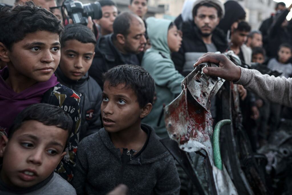 Niños, mujeres y hombres palestinos observan la destrucción que dejan los ataques de Israel en la zona de Rafah en la Franja de Gaza de Palestina.