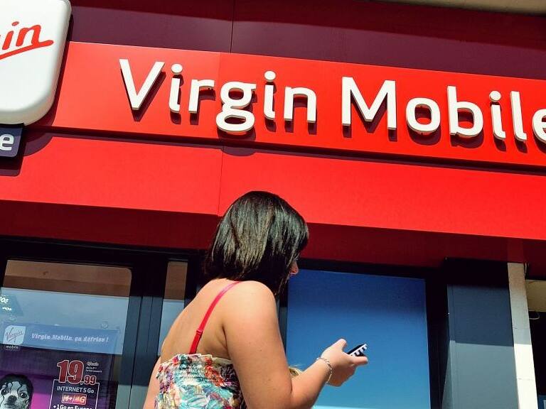 A woman gives a phone call as she walks by a shop of mobile phone operator Virgin Mobile on May 17, 2014 in Lens. AFP PHOTO PHILIPPE HUGUEN (Photo by Philippe HUGUEN / AFP) (Photo credit should read PHILIPPE HUGUEN/AFP via Getty Images)