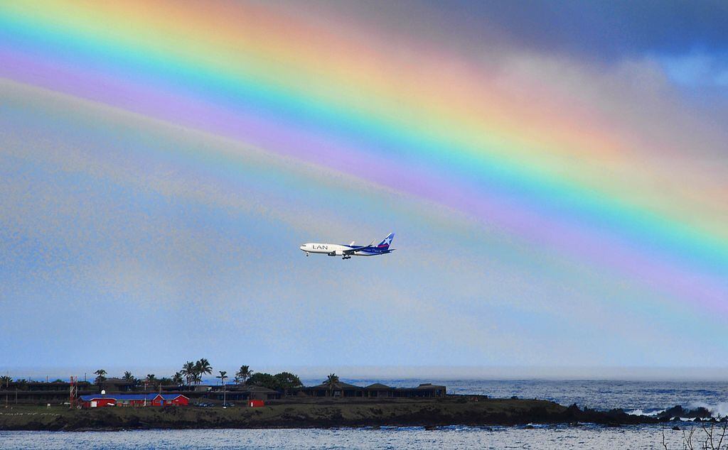 A plane is seen next to the rainbow on Ankaroa bay in Easter Island, 3700 km off the Chilean coast in the Pacific Ocean, on July 12, 2010. AFP PHOTO/Martin Bernetti (Photo credit should read MARTIN BERNETTI/AFP via Getty Images)