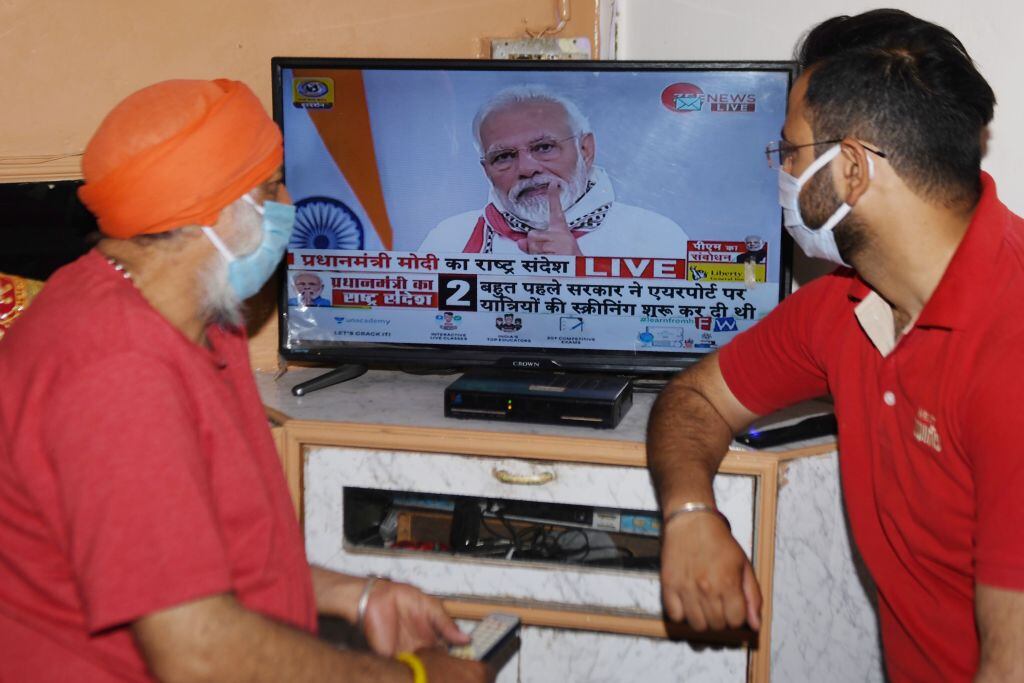 Dos habitantes de la India escuchan el mensaje del el primer ministro Narendra Modi
