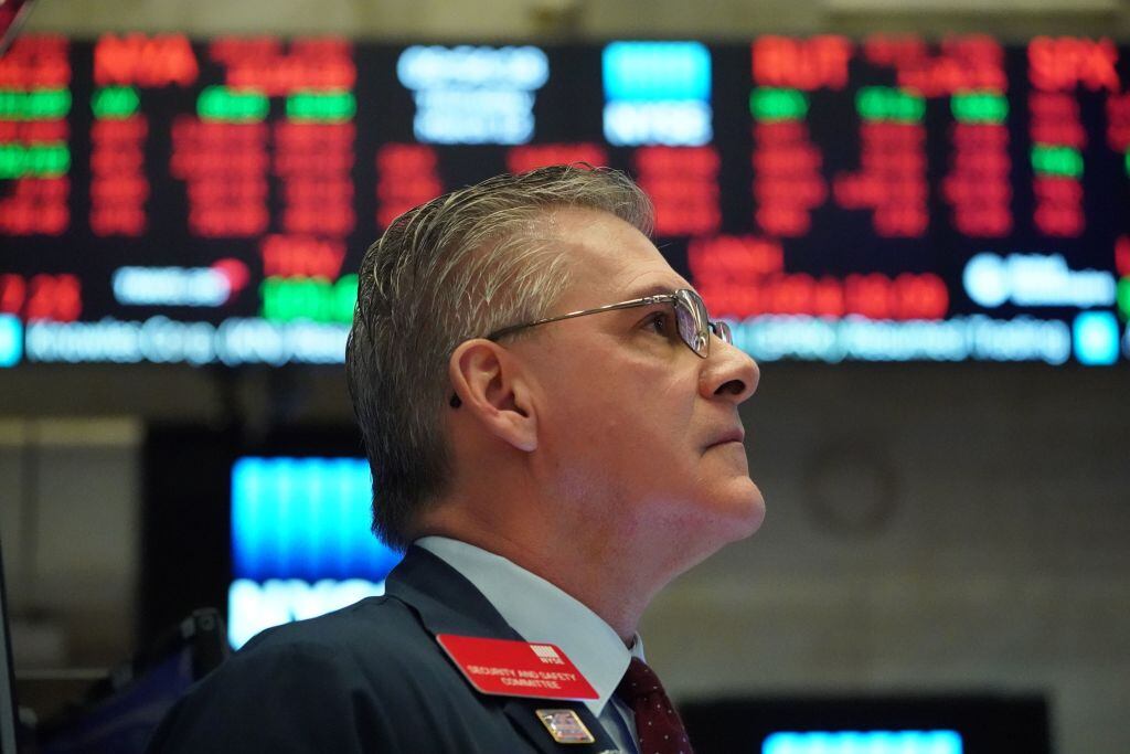 Un funcionario de la bolsa observa los índices rojos de la pizarra en Wall Street