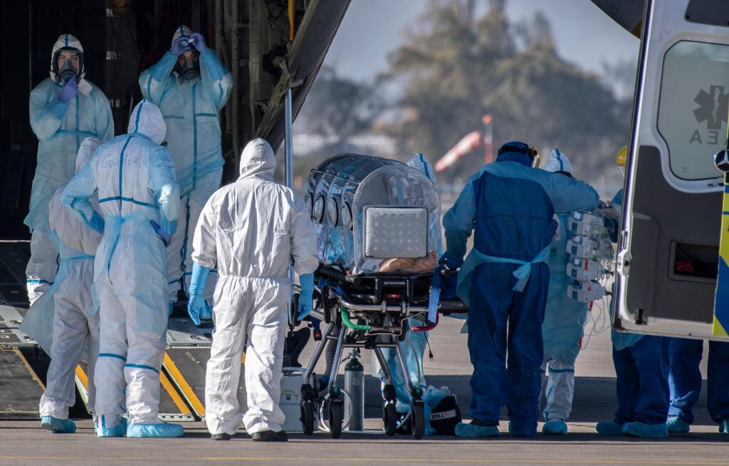 TOPSHOT - Health workers move a COVID-19 infected patient to a C-130 Hercules, to be taken to the city of Concepcion, at a Chilean Air Force base in Santiago, Chile, on May 24, 2020. - Patients infected with COVID-19 are taken to other cities in the country in order to free up space in the intensive care units of hospitals in Santiago. (Photo by Martin BERNETTI / AFP) (Photo by MARTIN BERNETTI/AFP via Getty Images)