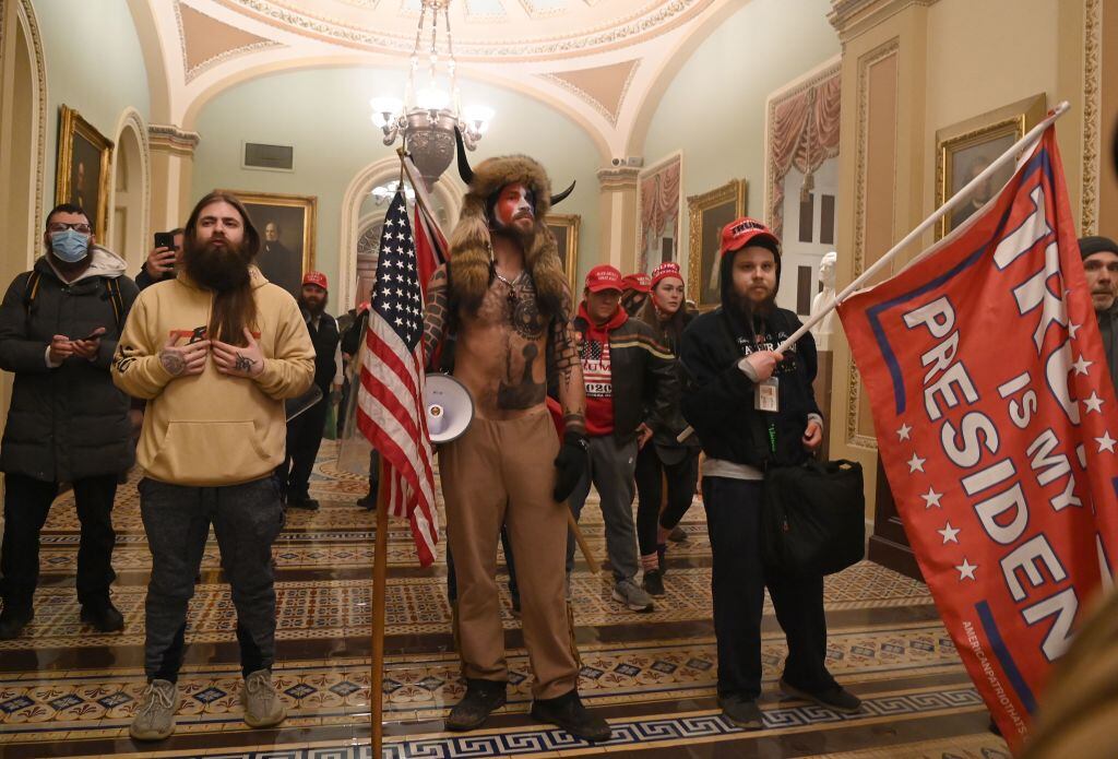 Chansley junto a un grupo de fanáticos de Trump en los pasillos del Capitolio