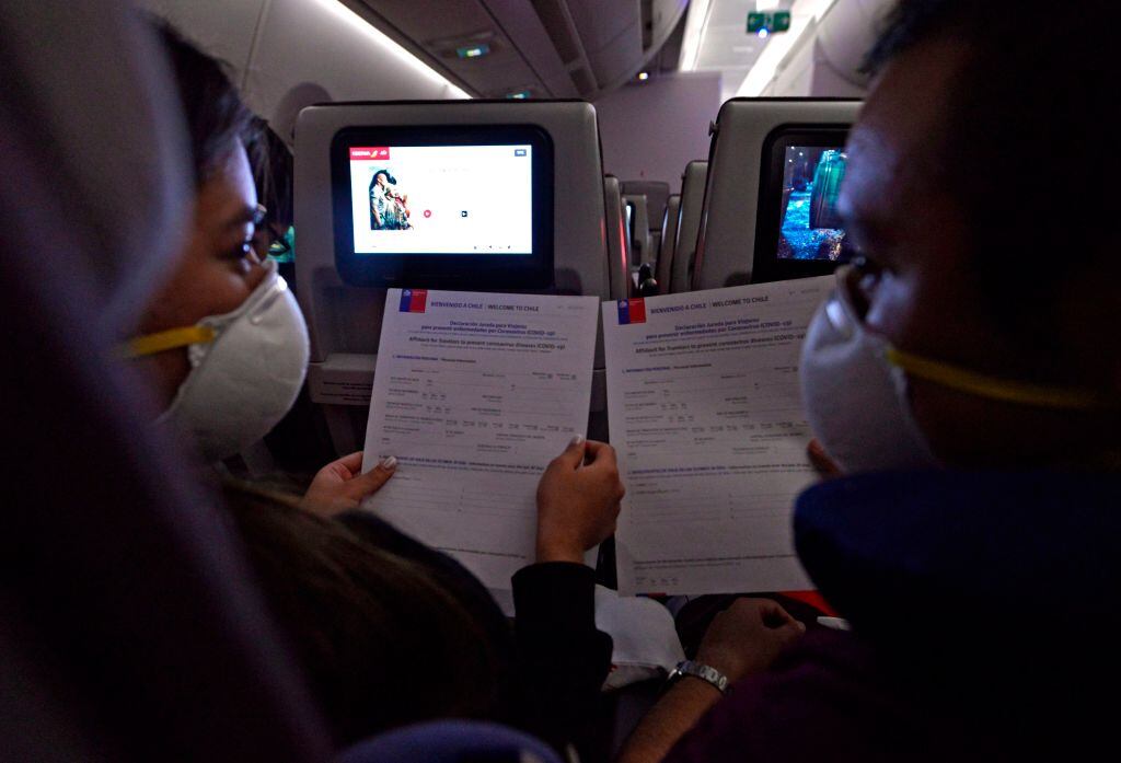 Passengers wear face masks to prevent the spread of the new Coronavirus, COVID-19, as they wait to disembark from a plane that arrived in Santiago on March 20, 2020. - Chile declared a "state of catastrophe" and delayed a constitutional referendum while several countries announced nighttime curfews as Latin America expanded its coronavirus lockdown on Wednesday. (Photo by PAOLO AVILA / AFP) (Photo by PAOLO AVILA/AFP via Getty Images)