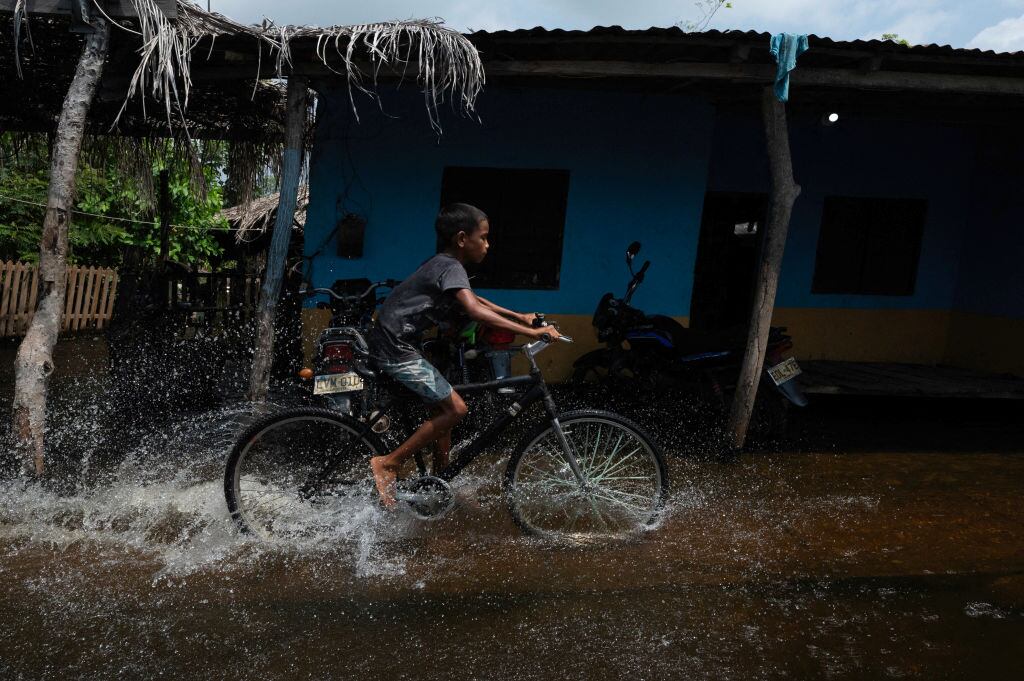 Un niño avanza en bicicleta por las calles inundadas de la localidad La Mojana en la provincia del Cauca en Colombia