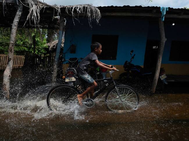 Un niño avanza en bicicleta por las calles inundadas de la localidad La Mojana en la provincia del Cauca en Colombia
