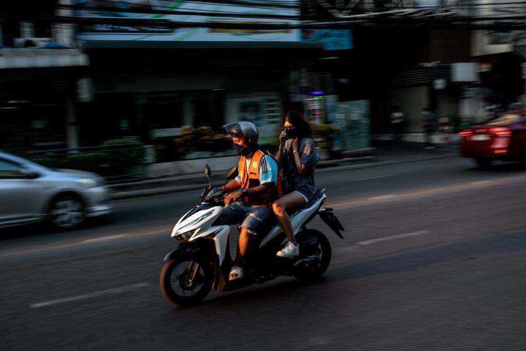A woman rides on the back of a motorbike taxi in Bangkok on December 18, 2020. (Photo by Jack TAYLOR / AFP) (Photo by JACK TAYLOR/AFP via Getty Images)