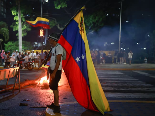 CARACAS, VENEZUELA - JULY 29: A demonstrator holds up a Venezuelan flag during a protest against the official results of the presidential election on July 29, 2024 in Caracas, Venezuela. Incumbent president Maduro was announced as the winner of a controversial presidential election with the 51,20% of the votes while opposition candidate Edmundo Gonzalez of the Plataforma Unitaria Democr·tica Coalition got the 44,2% according to the 'Consejo Nacional Electoral' CNE (National Electoral Council) (Photo by Jesus Vargas/Getty Images)
