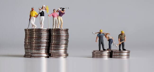 Concept of the gap between rich and poor. Miniature people standing on a pile of coins.