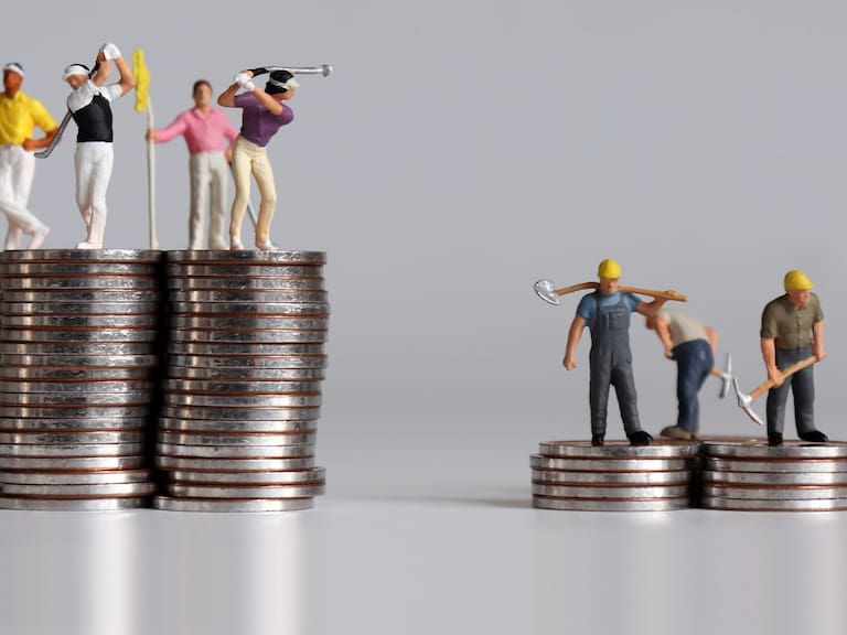 Concept of the gap between rich and poor. Miniature people standing on a pile of coins.